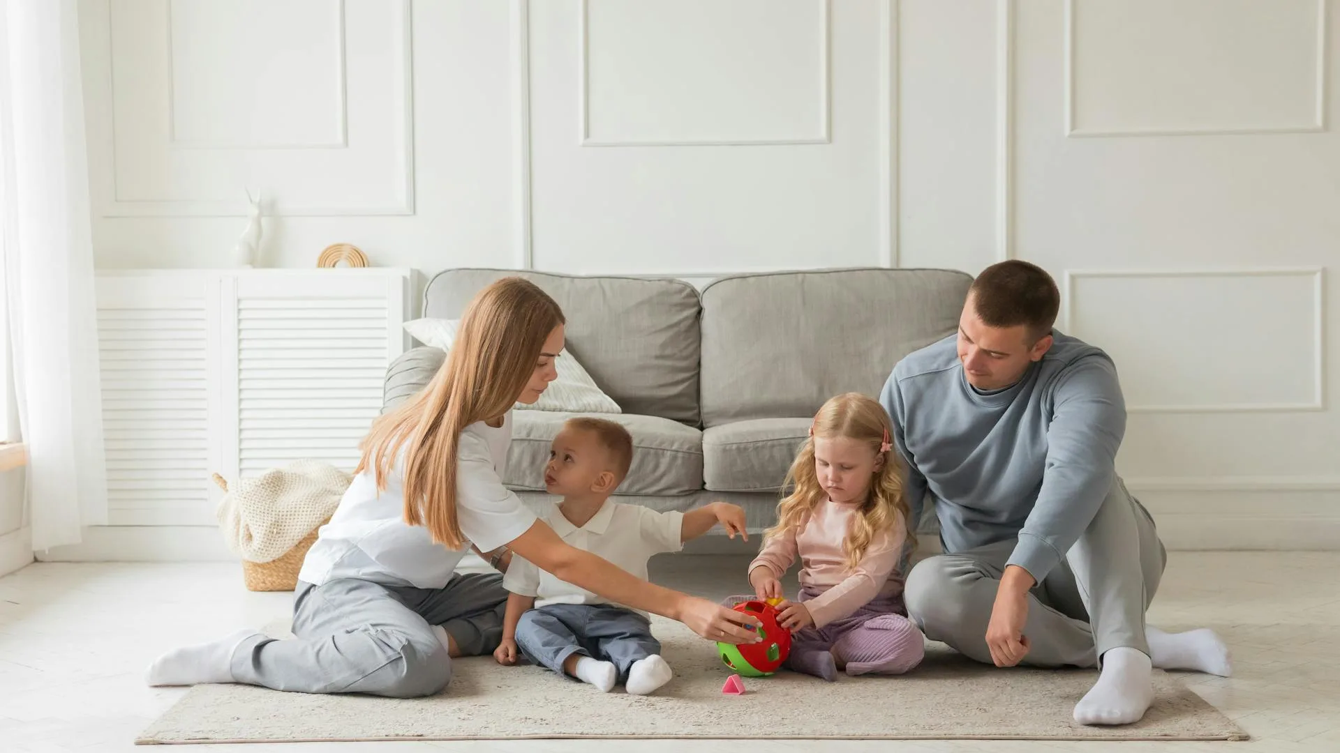 A bright, styled living room with a family playing on the floor