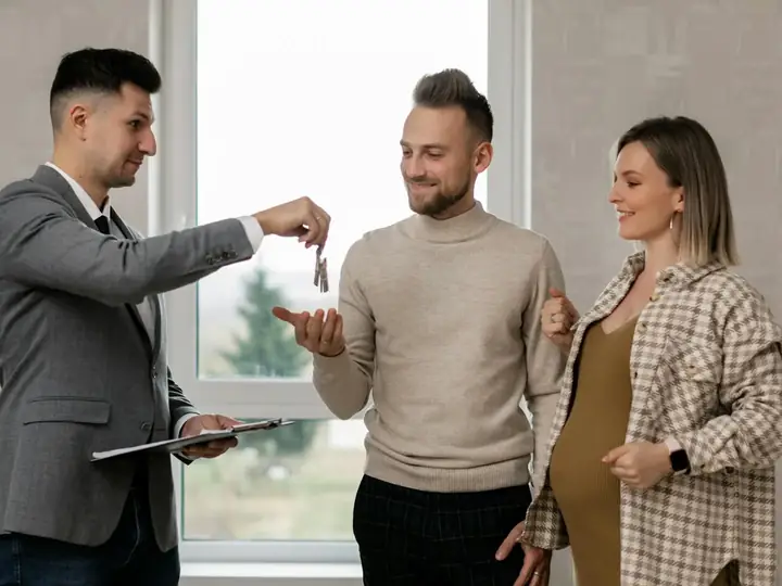 An agent handing house keys to a happy couple