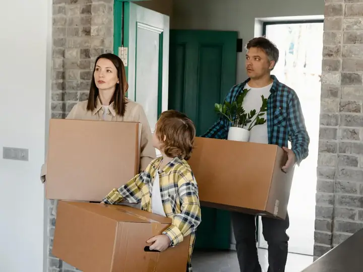 A family carrying moving boxes into their next home